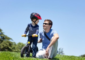 happy smiling father with his son on a balance bike